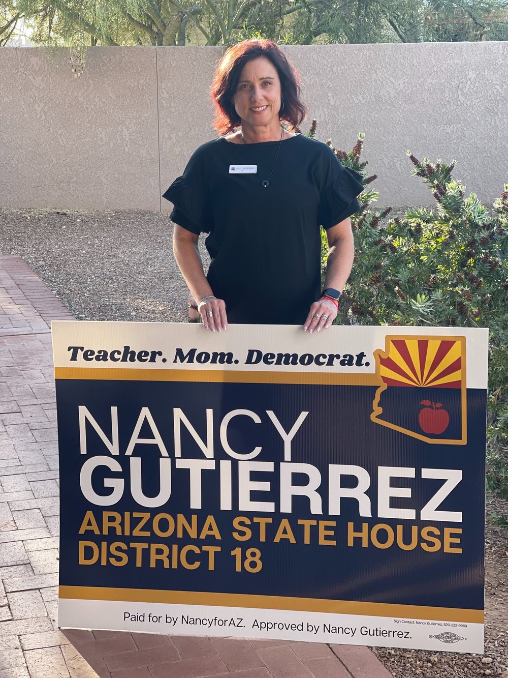 Nancy Gutierrez standing with one of her campaign yard signs